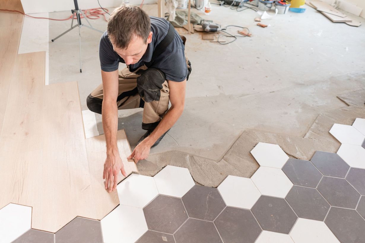 Installer laying hexagonal floor tiles in a room under renovation