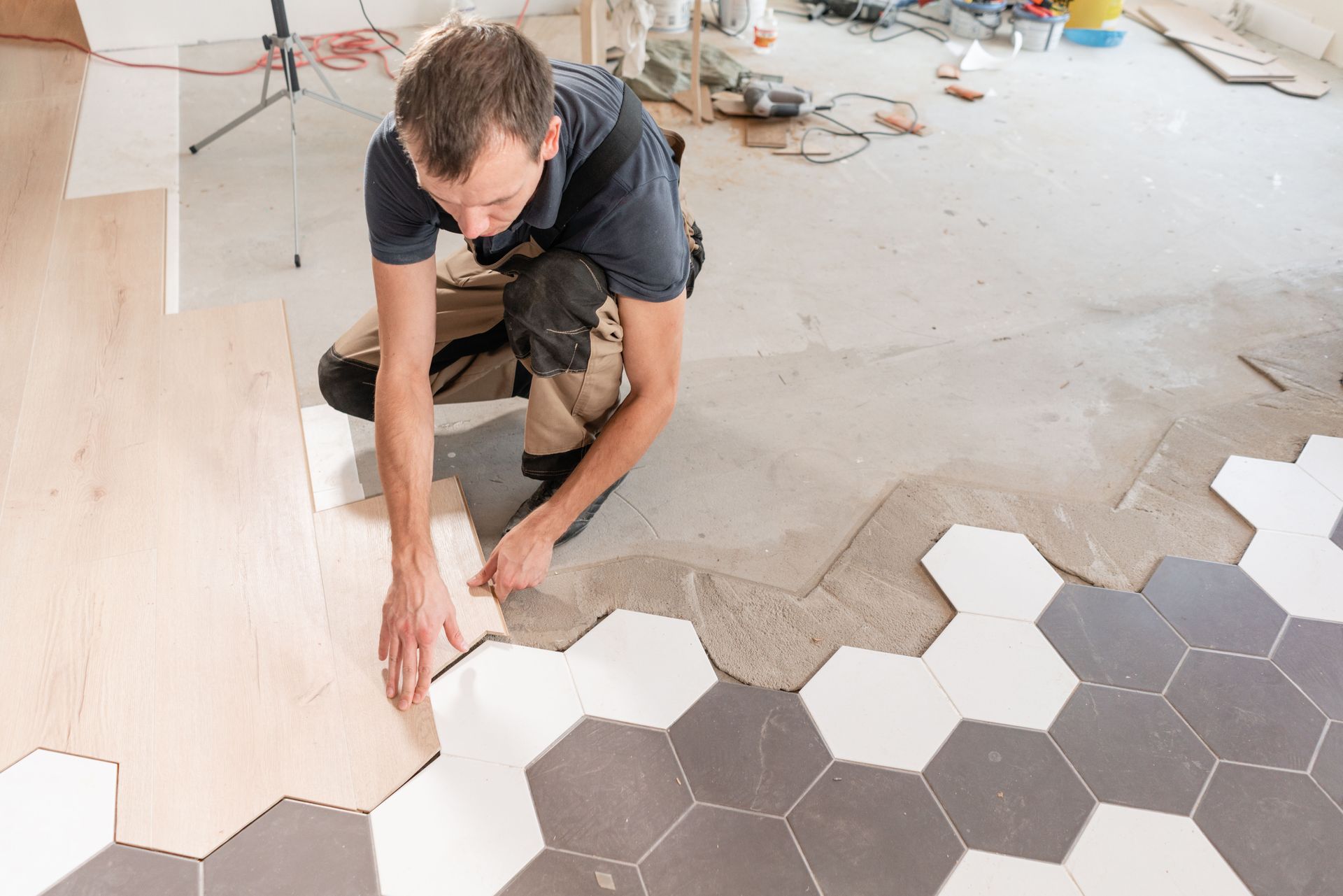 Installer laying hexagonal floor tiles in a room under renovation
