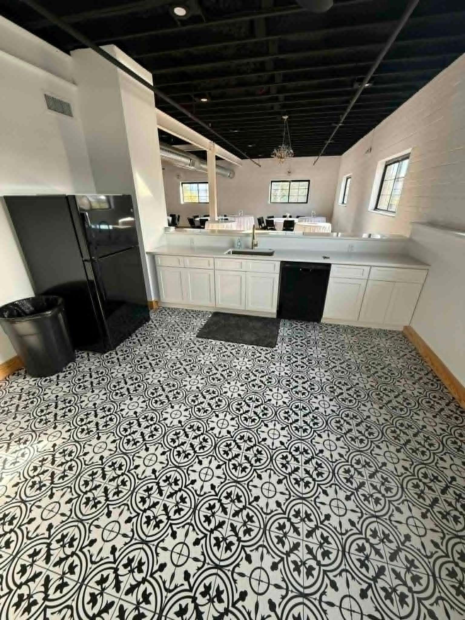 Modern kitchen with white cabinets, black appliances, and patterned black-and-white tile floor