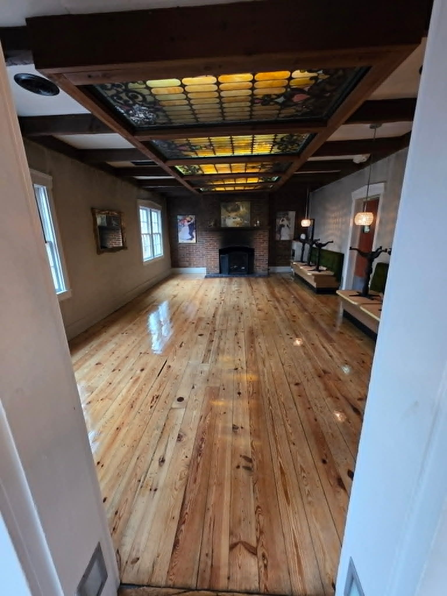 Empty modern interior with glossy wood floor, white walls, skylights, and exposed beams.