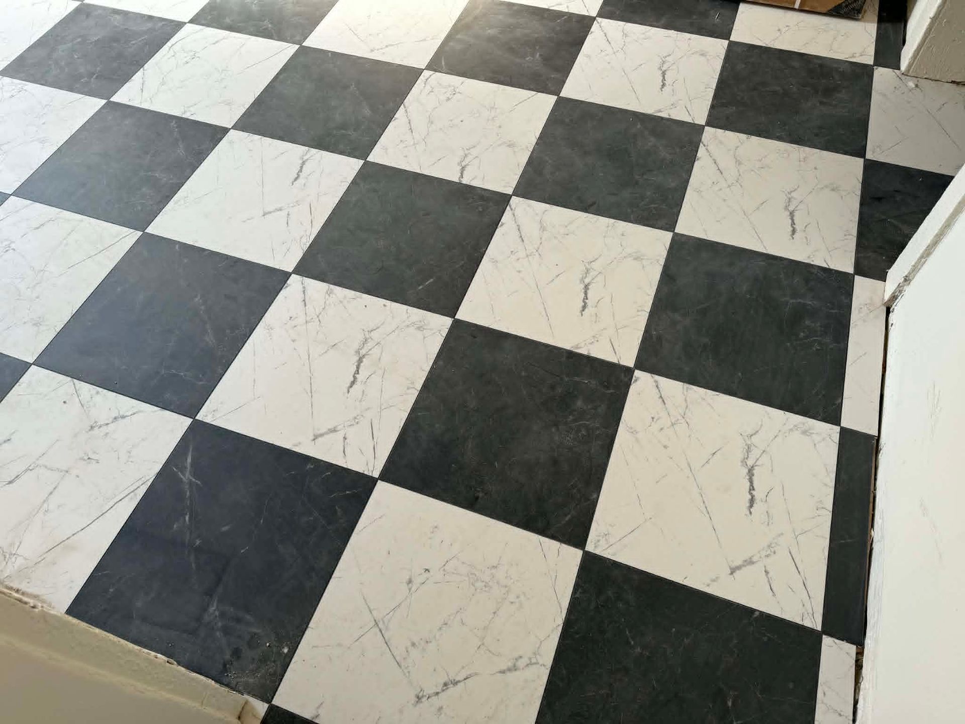 Black-and-white checkerboard floor tiles with light scuff marks in a tiled room