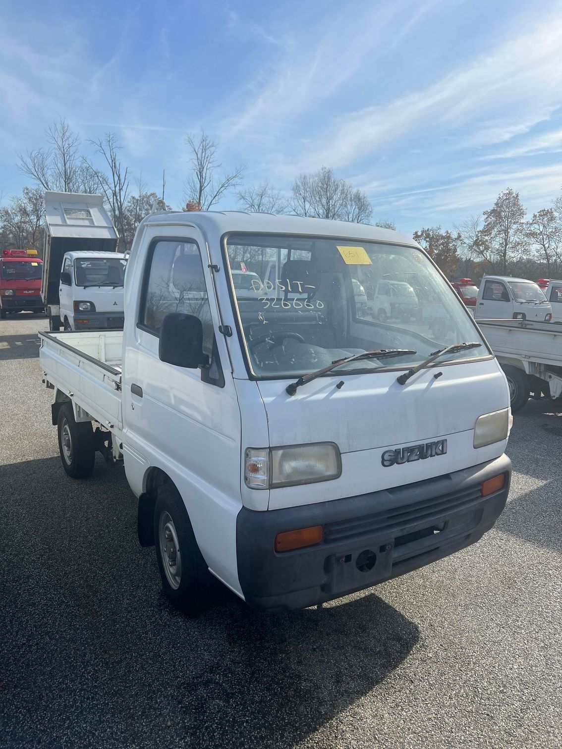 A white truck is parked in a gravel lot.
