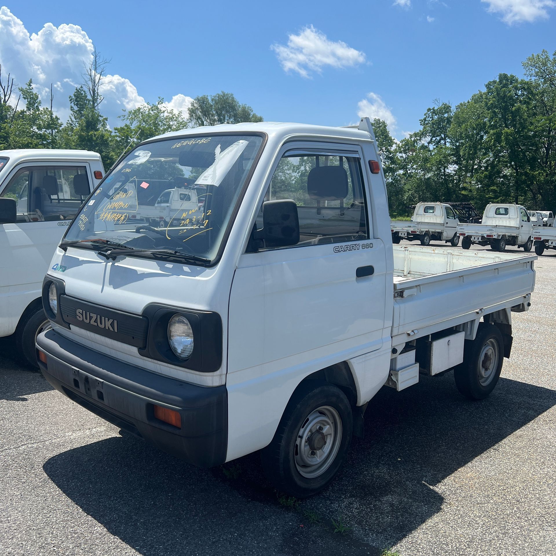 A white suzuki truck is parked in a parking lot
