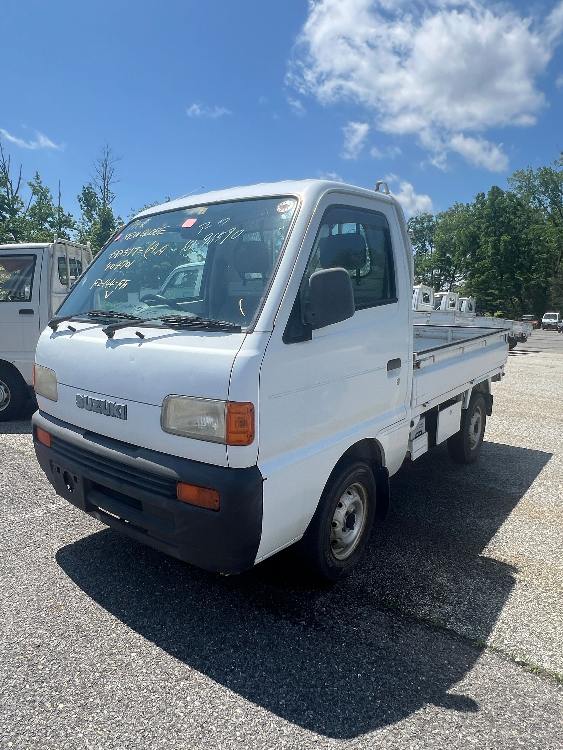 Two white trucks are parked next to each other in a parking lot.