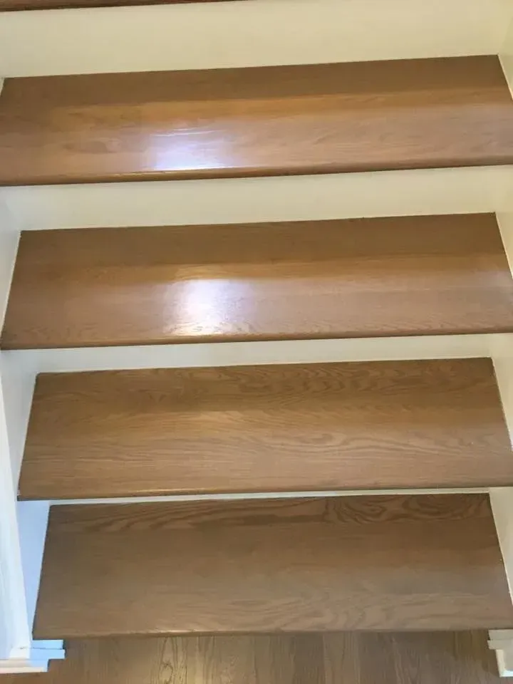 Four wooden stair treads with white risers viewed from directly above.