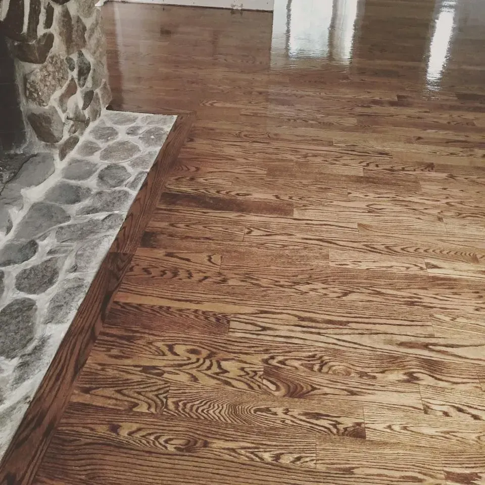 Light-toned hardwood flooring with a distinct grain pattern running adjacent to a stone fireplace hearth.