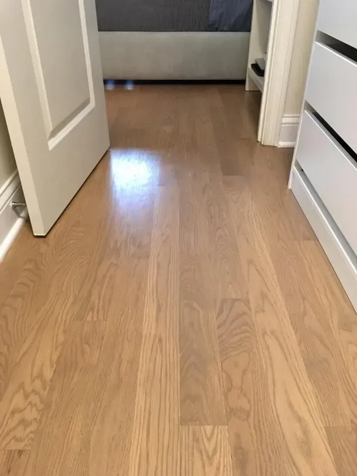 Light-toned hardwood flooring stretches from the foreground into a bedroom doorway.