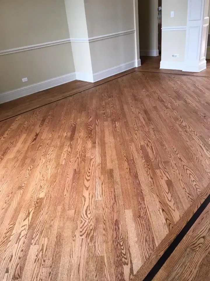 Hardwood floor with a diagonally laid central section bordered by straight-plank transition strips in a room.