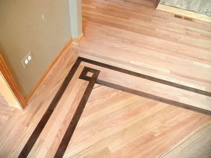 Light hardwood floor with a decorative dark wood border forming a square accent in the corner.