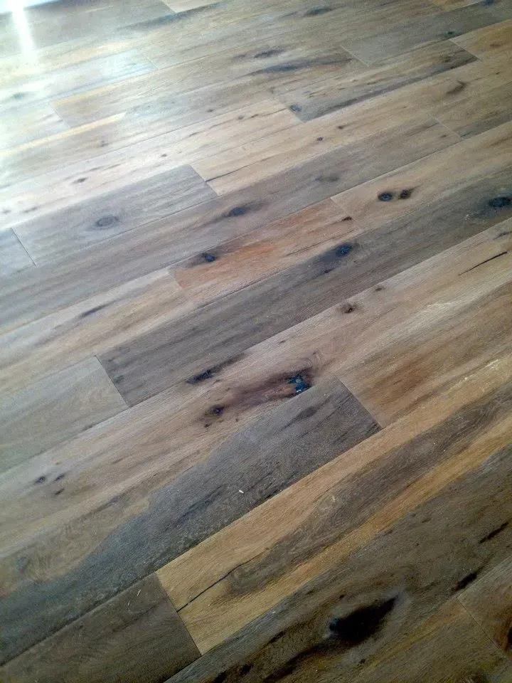 Rustic-style hardwood flooring featuring natural grain patterns, knots, and a varied mix of light and dark brown tones.