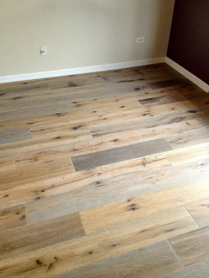 Light-colored wood flooring with varied grain patterns and knots, featuring light and dark brown planks in a room.