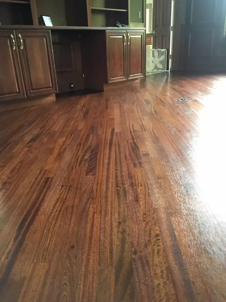 Polished dark wood flooring in a room with matching wooden cabinets and furniture.