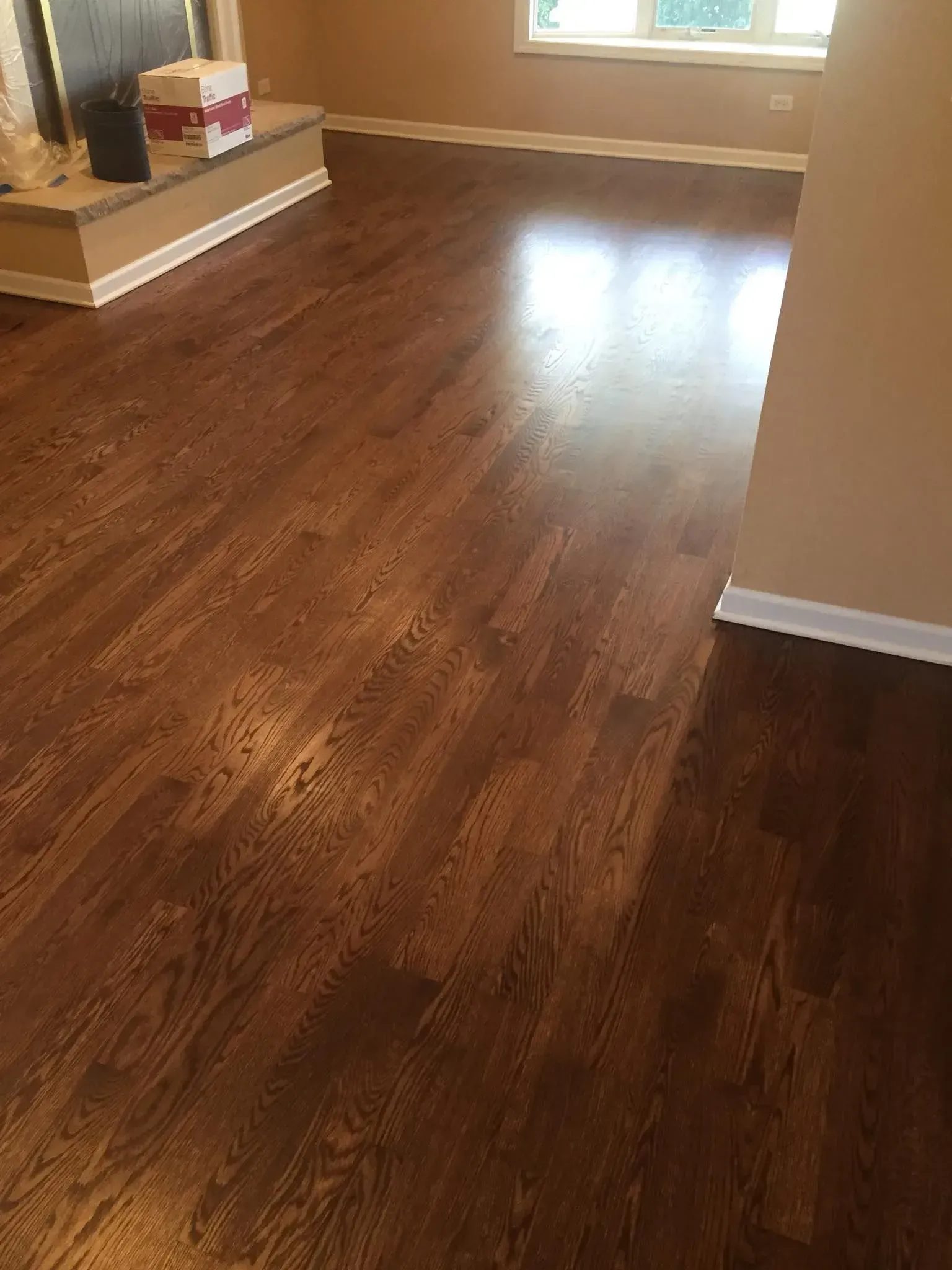 A room with dark brown hardwood flooring, beige walls, white trim, and a raised fireplace hearth.