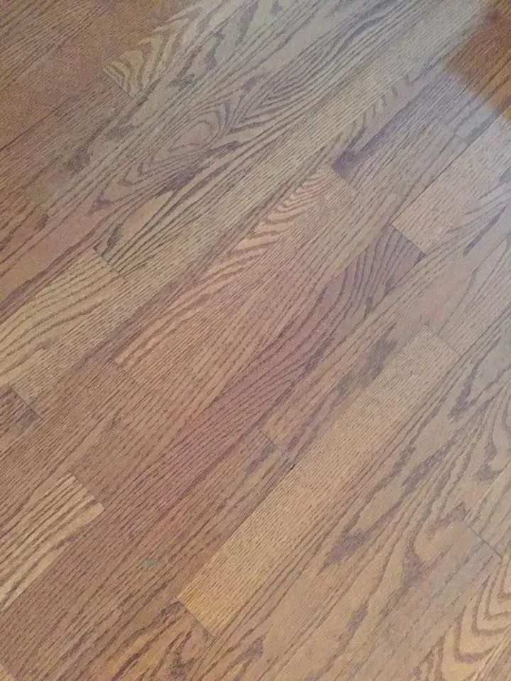 High-angle close-up of light brown wood flooring with prominent natural grain patterns and linear seams.