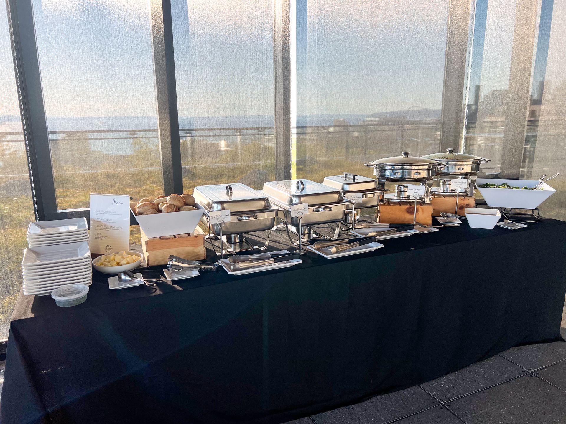 Buffet set up for a full service catered corporate event. Stainless steel chafers, wooden risers, and a black linen included.