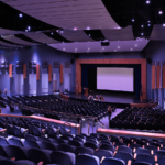 A large auditorium with rows of seats and a large screen