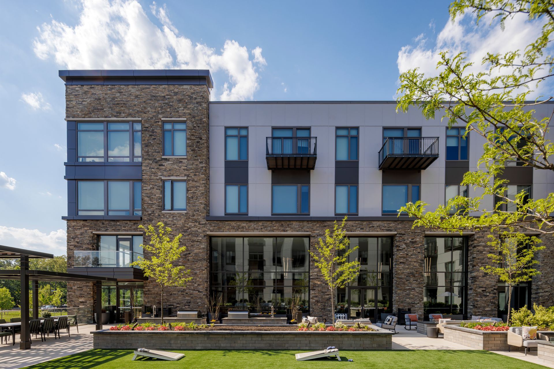 A large apartment building with a lot of windows and a lawn in front of it.