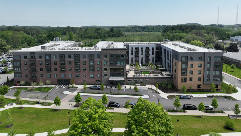 An aerial view of a large apartment building with a lot of cars parked in front of it.