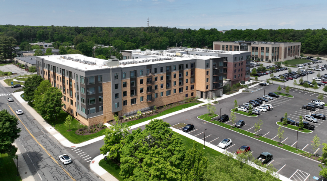 An aerial view of a large apartment building with a parking lot in front of it.