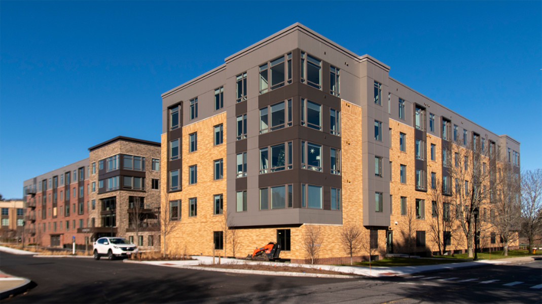 A large apartment building with a lot of windows on a sunny day.