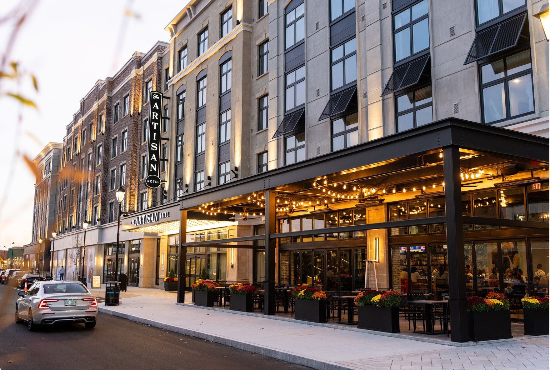A car is driving down a street in front of a large building.