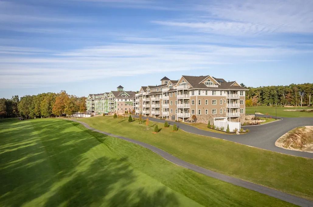 An aerial view of a large apartment building next to a golf course.