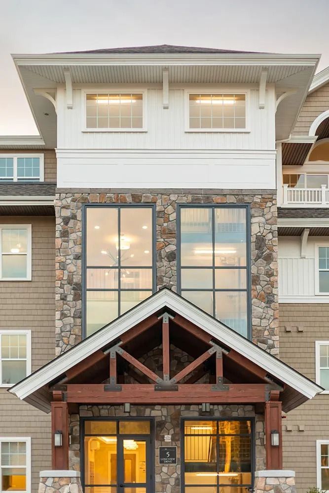 The front of a large building with a stone facade and lots of windows.