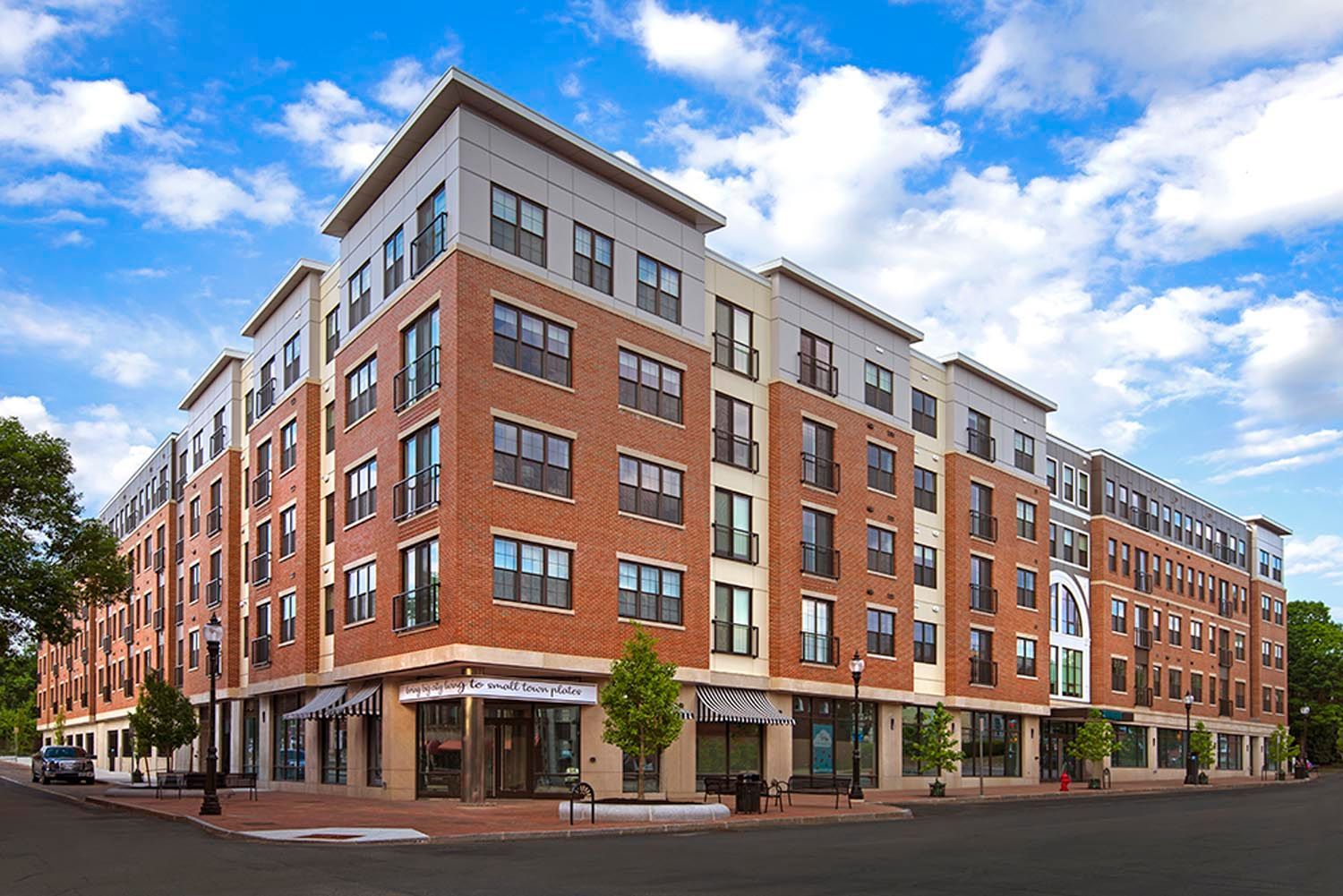 A large brick building with a lot of windows is on the corner of a street.