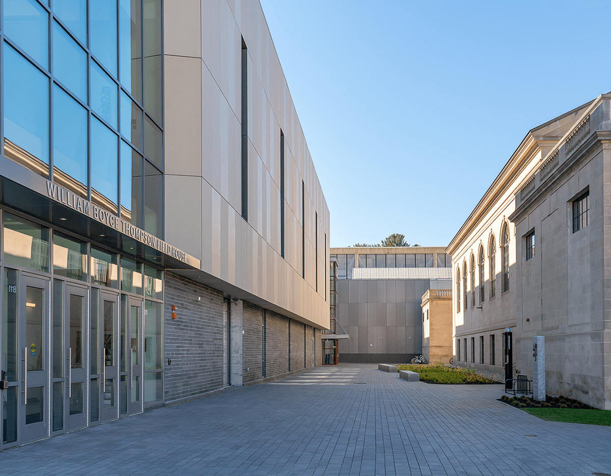 A large building with a lot of windows is surrounded by smaller buildings.