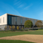A large building with a baseball field in front of it.