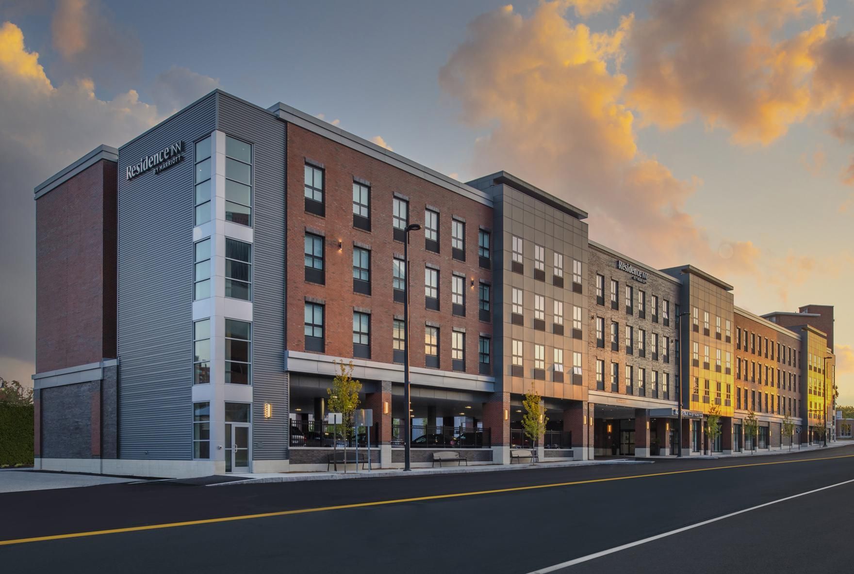 A large brick building with a lot of windows is sitting on the side of a road.