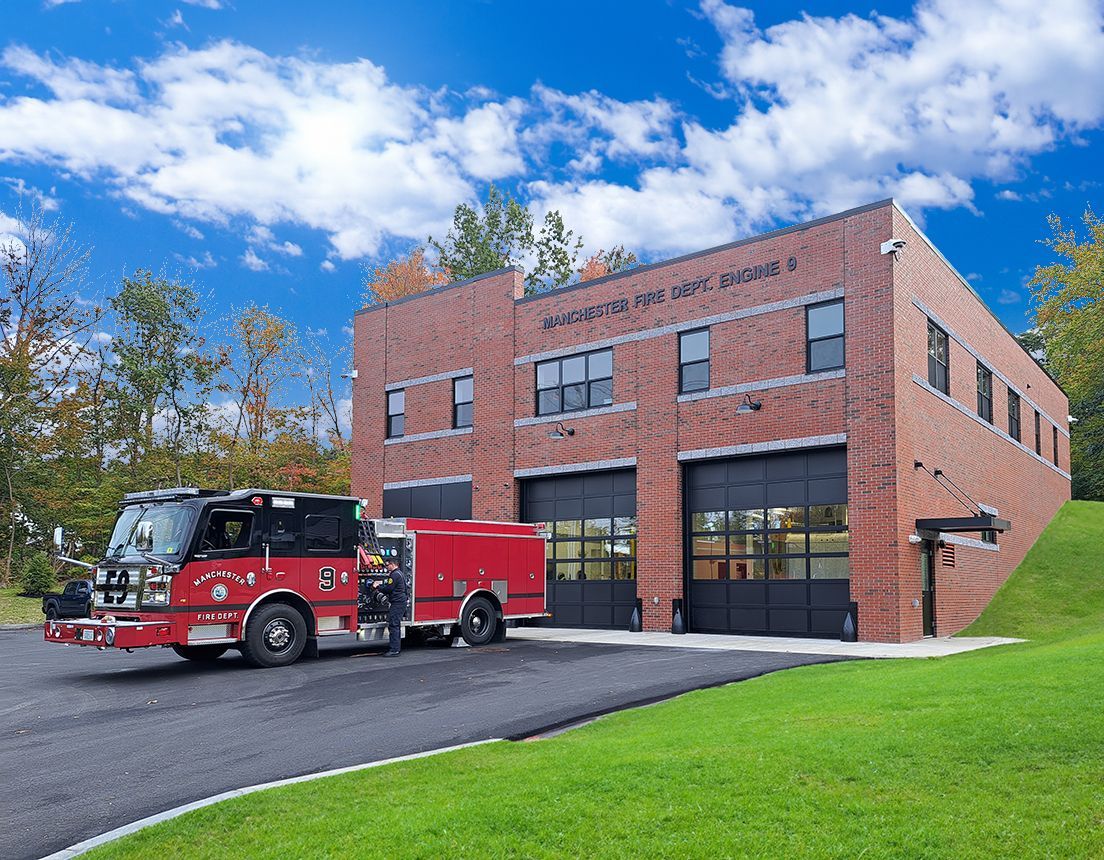 A red fire truck is parked in front of a brick building.