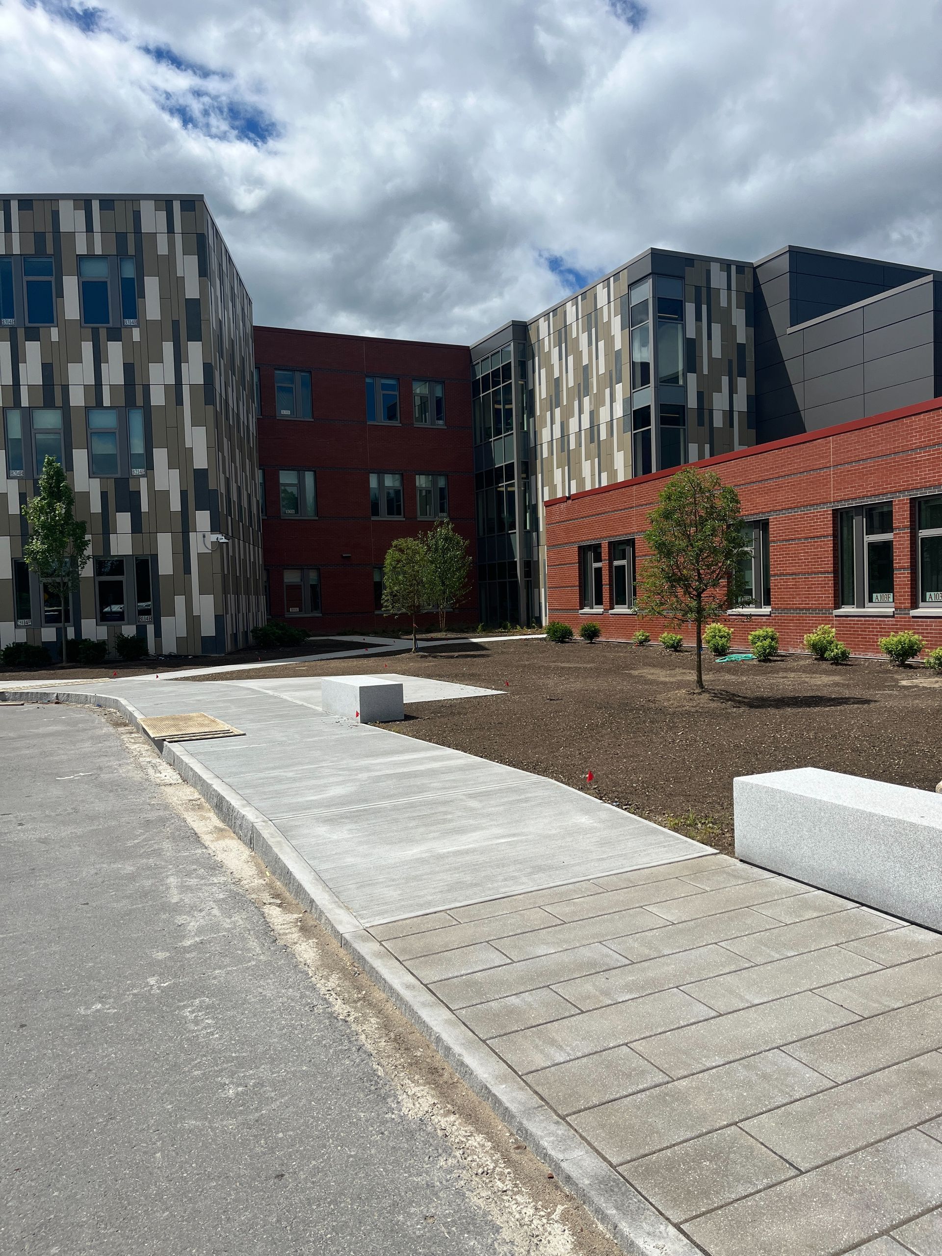 A large building with a lot of windows is sitting next to a sidewalk.