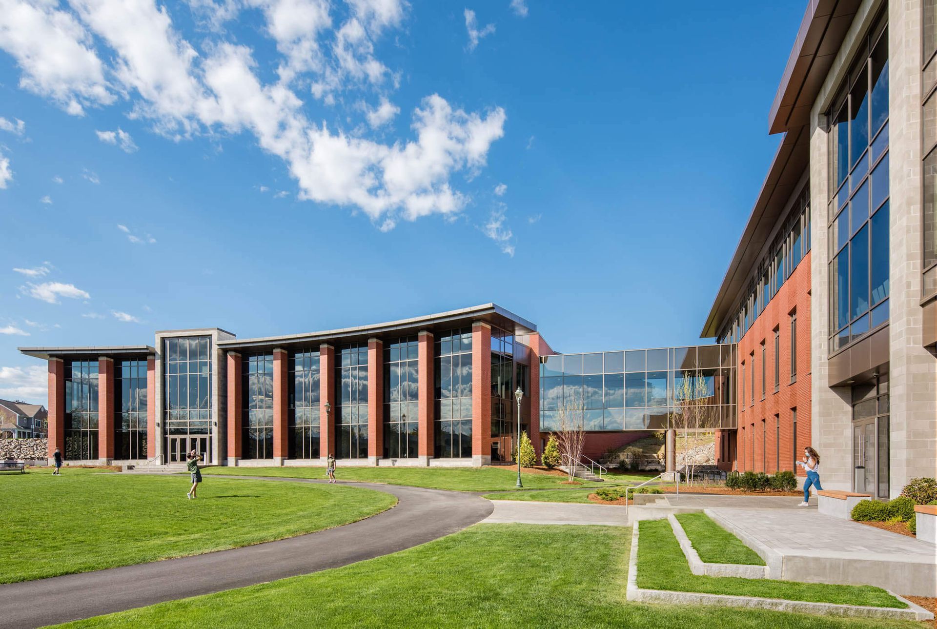 A large building with a lot of windows is sitting on top of a lush green field.