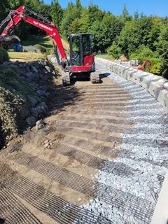 A red excavator is driving down a dirt road.