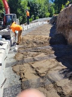 A stone wall is being built next to a dirt road.