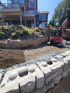 A large house is being built next to a large rock wall.