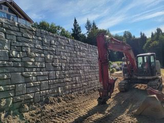 A red excavator is working on a brick wall.