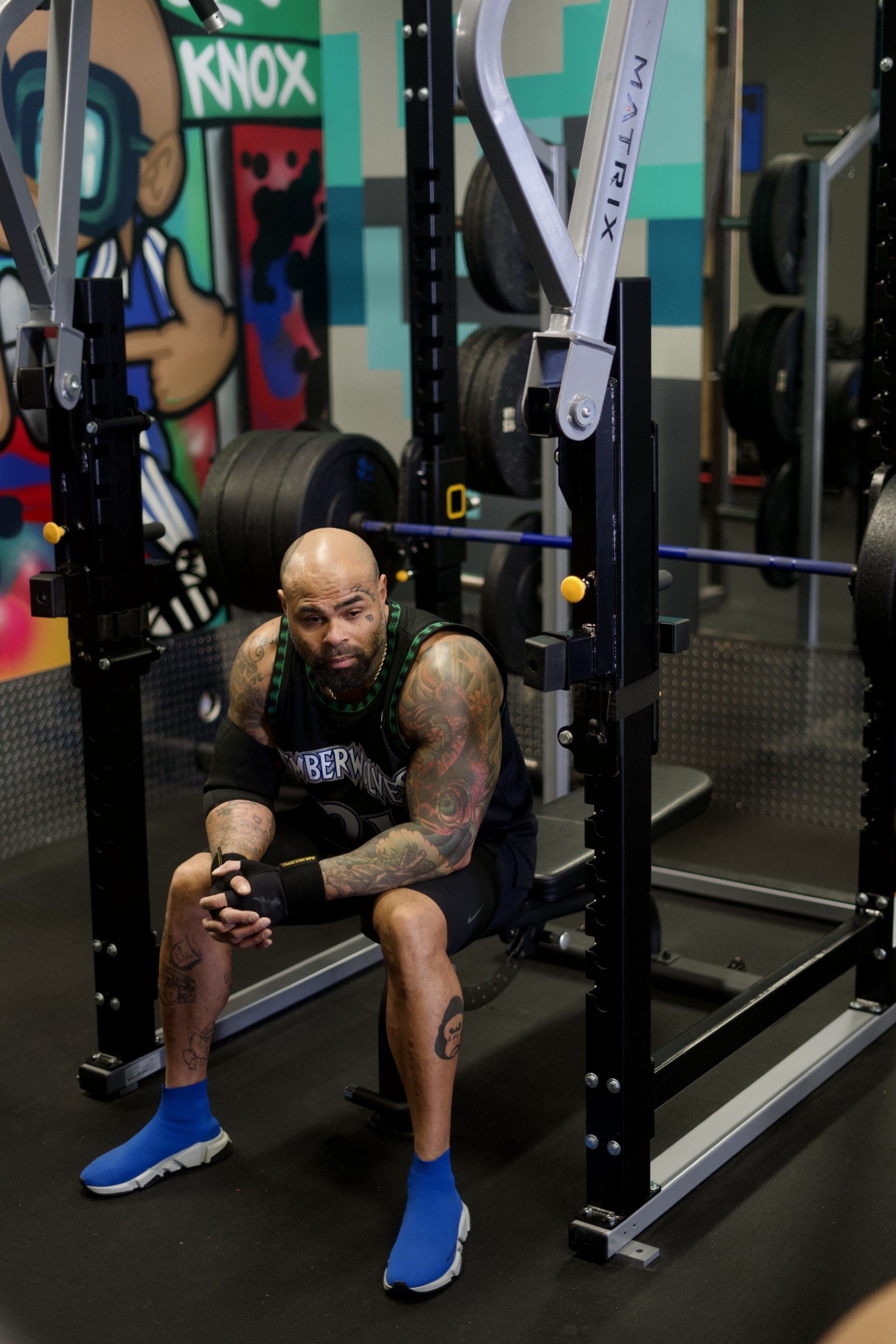 A man is sitting on a bench in a gym.