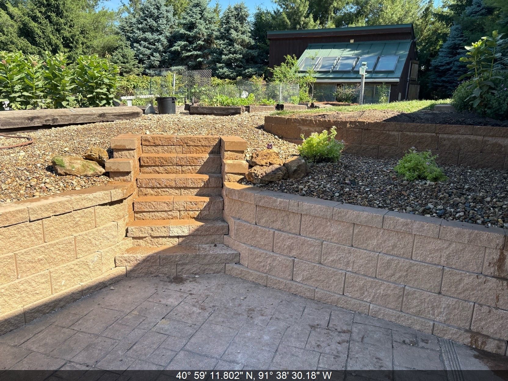 Stone steps and terraced retaining walls leading to a modern house amid trees and landscaping