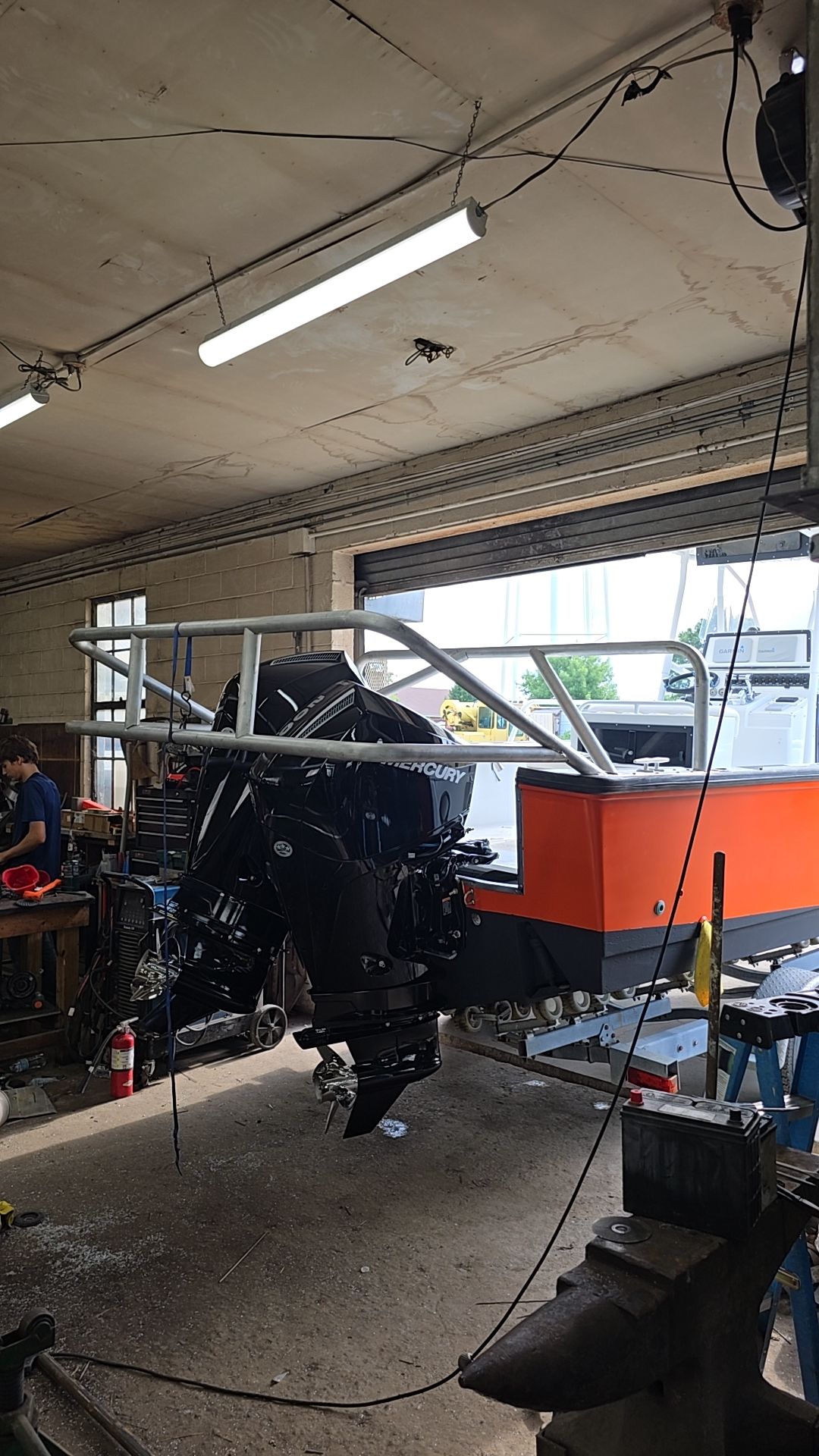A large black engine mounted on an orange platform with a metal frame, inside a workshop.