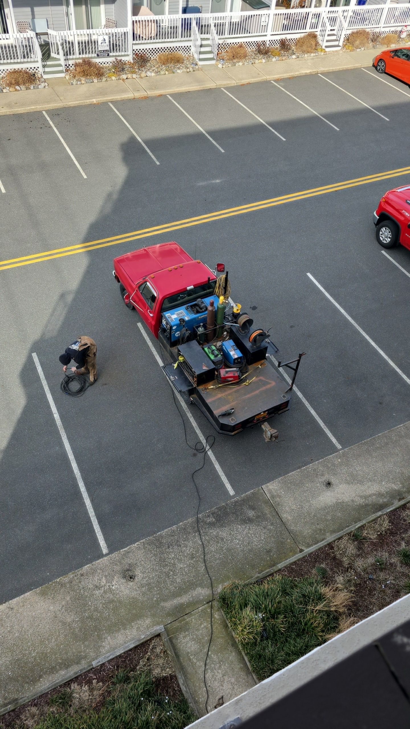 Red pickup truck with trailer parked in a lot; person near the truck.