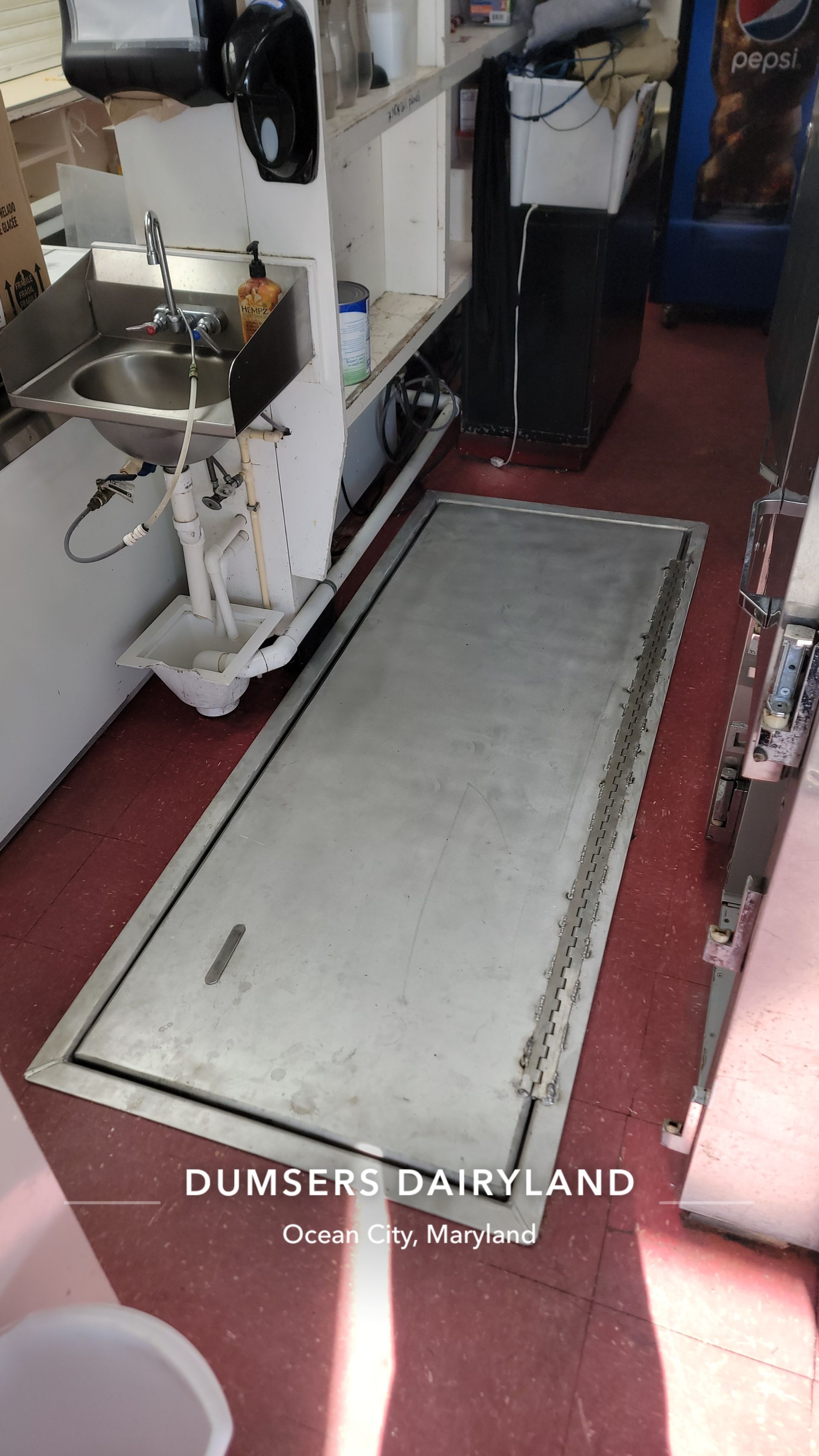 Stainless steel floor panel in a diner. Sink and equipment visible. 