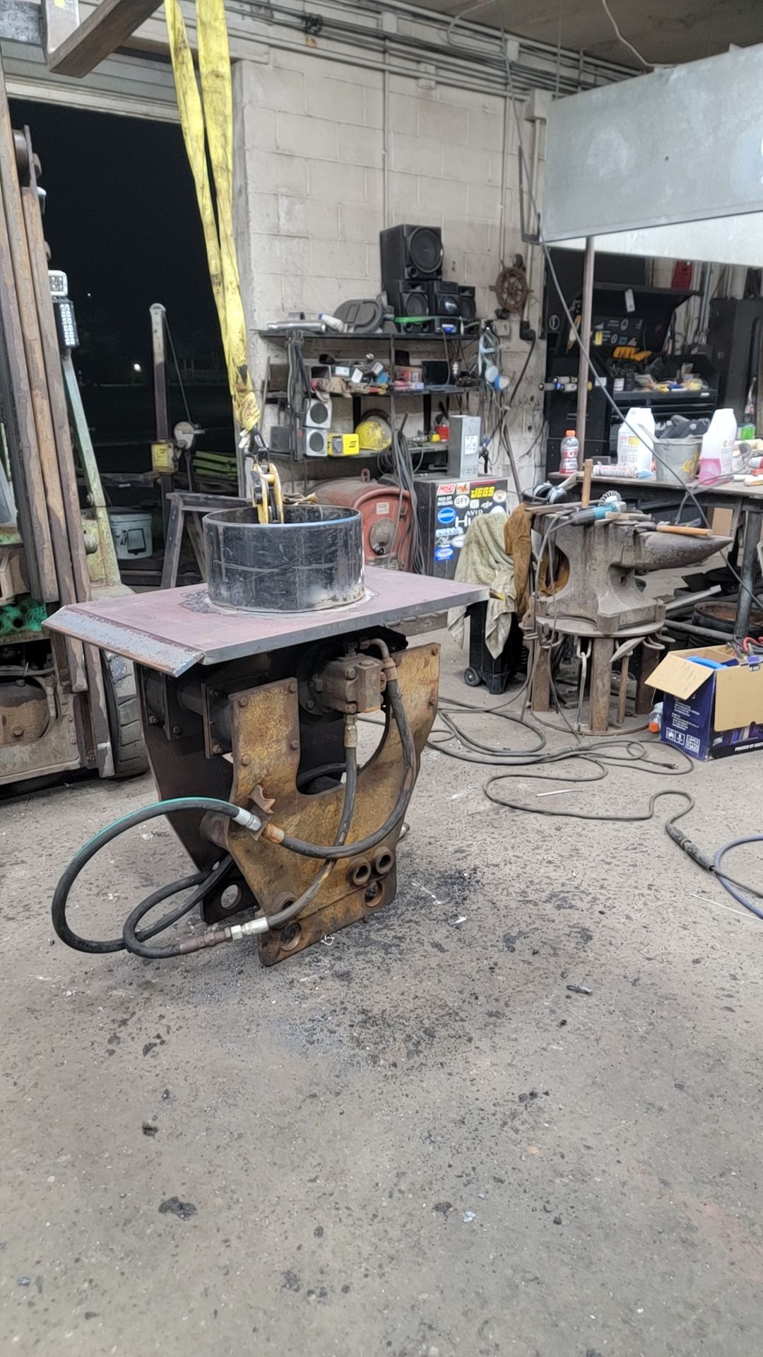 Metal fabrication workshop with machinery, tools, and a large metal structure being worked on.