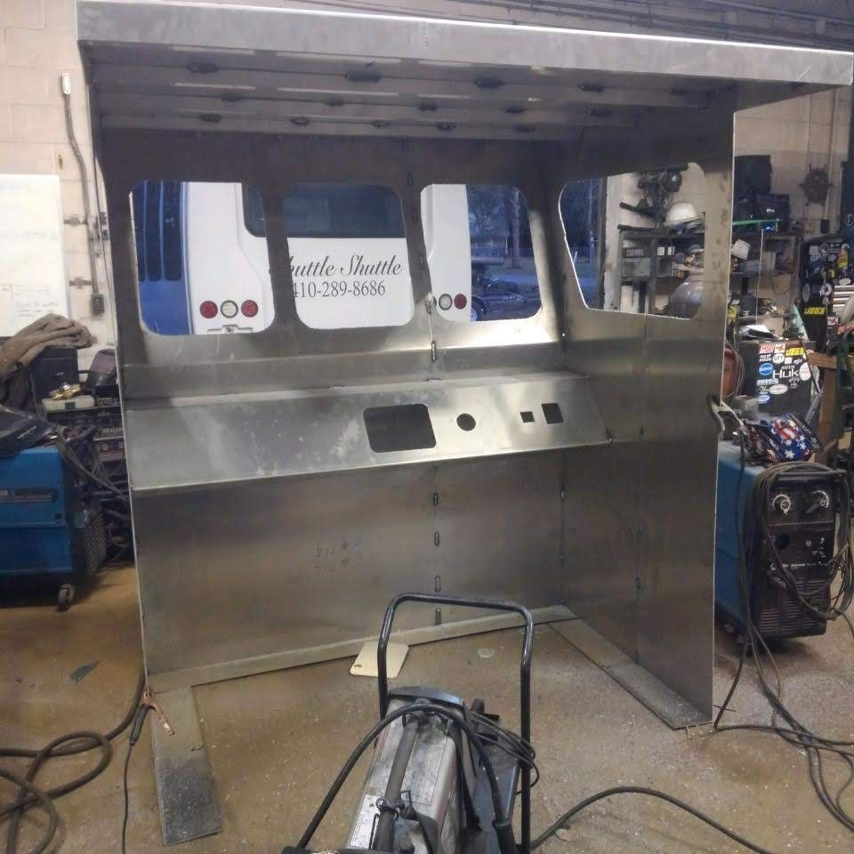 Metal structure with cutouts for windows and controls, in a workshop setting.