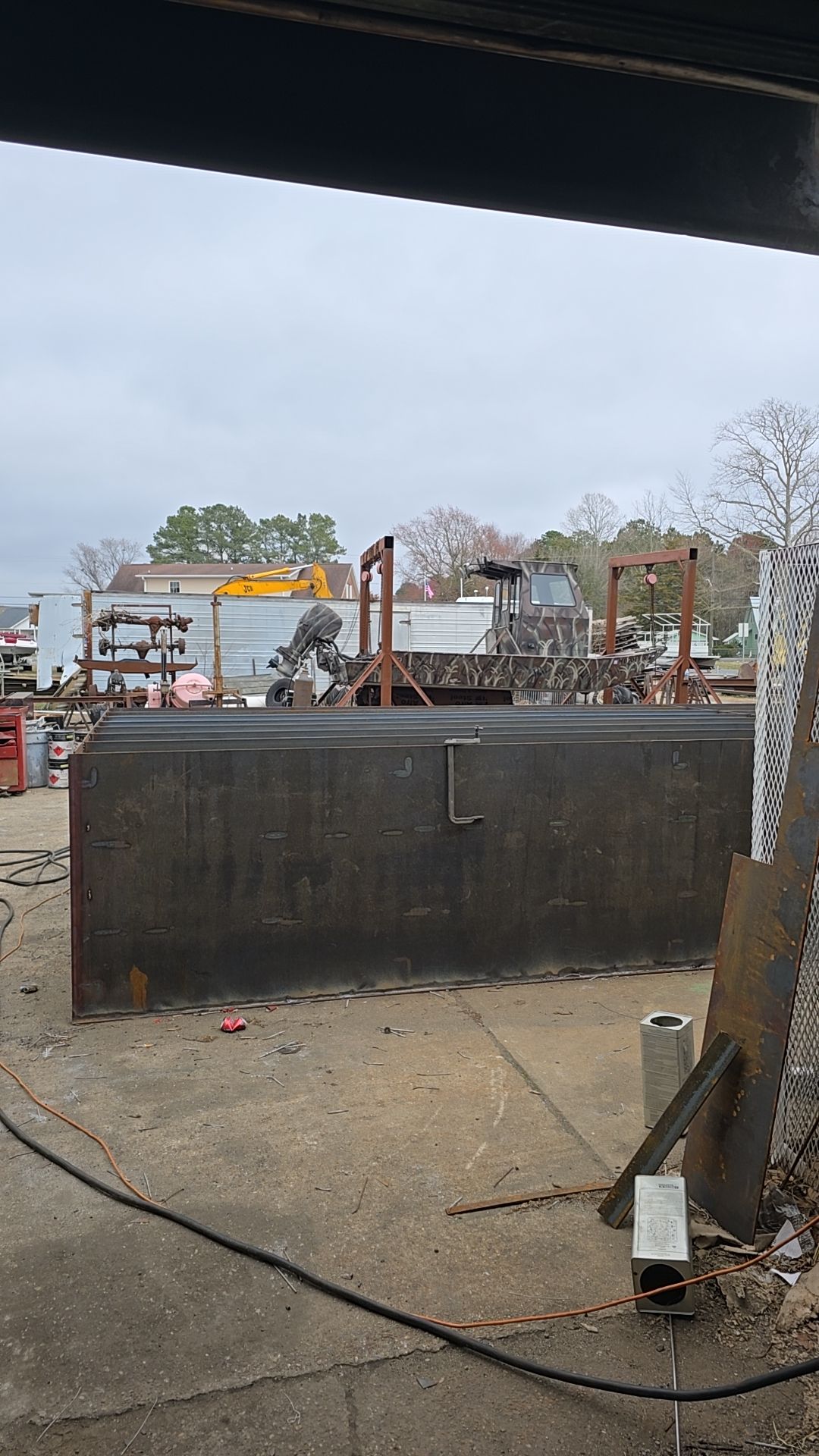 Metal structure outside with buildings and cloudy sky in the background.