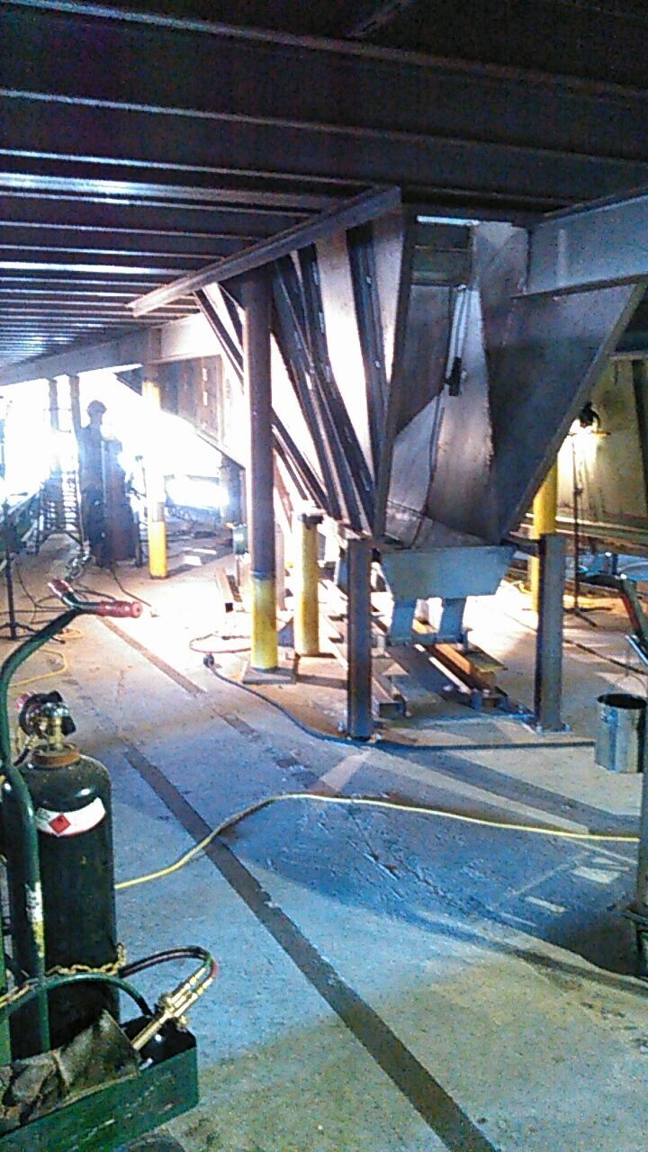 Steel industrial structure with beams and support legs under concrete floor.