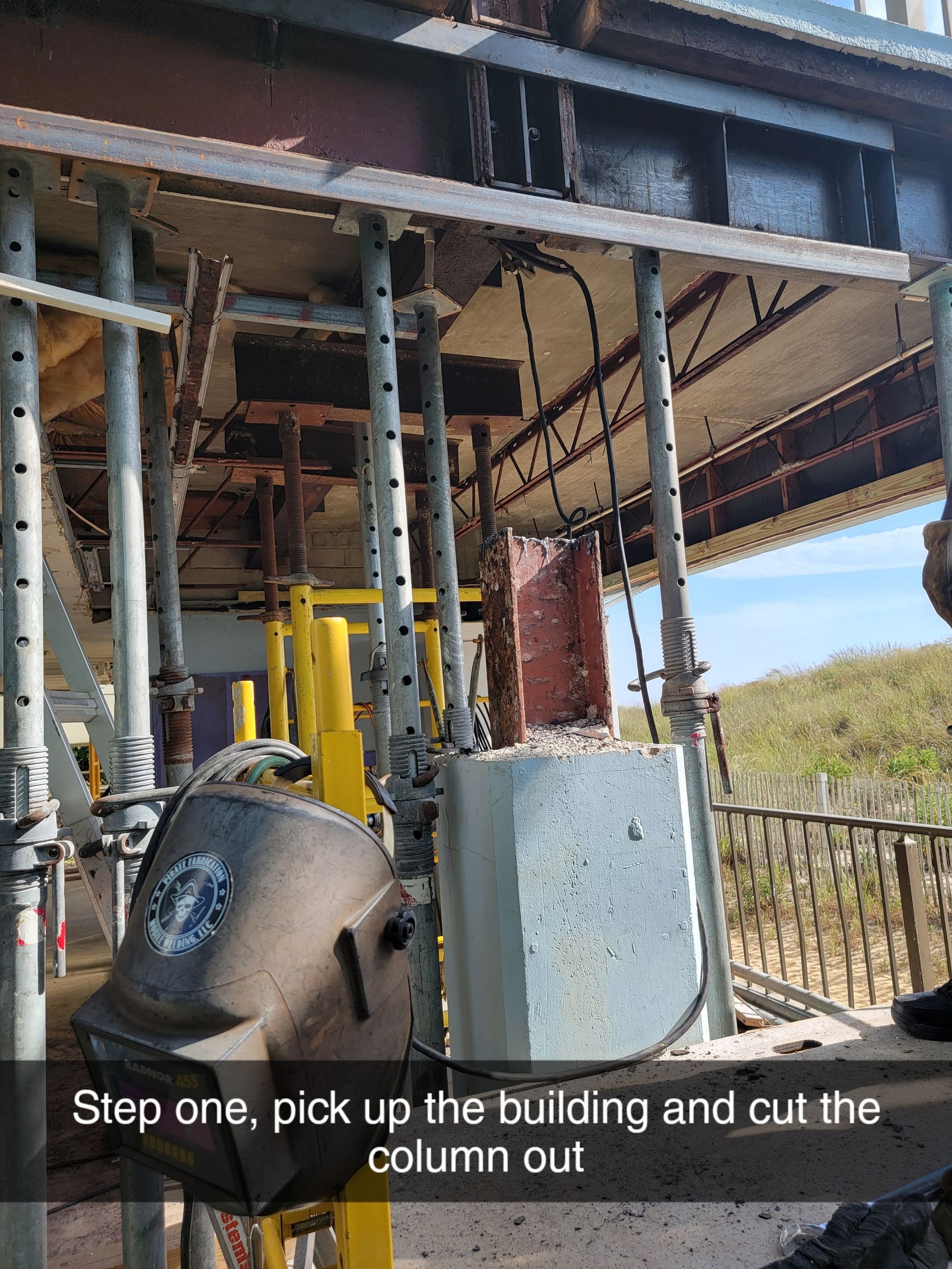 Construction site: Building supported by scaffolding, column being removed.