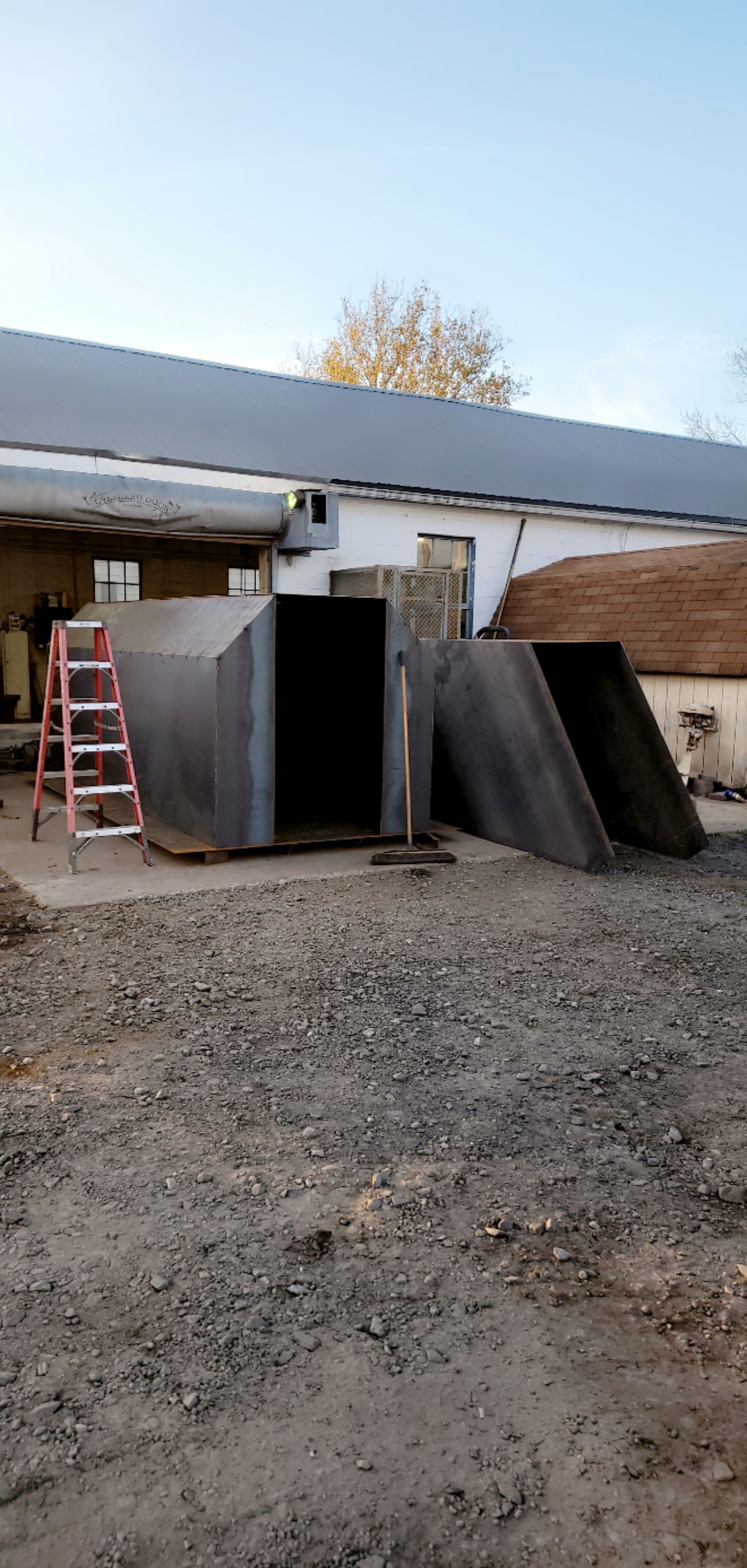 Steel shelter under construction, next to a building. A ladder is present.
