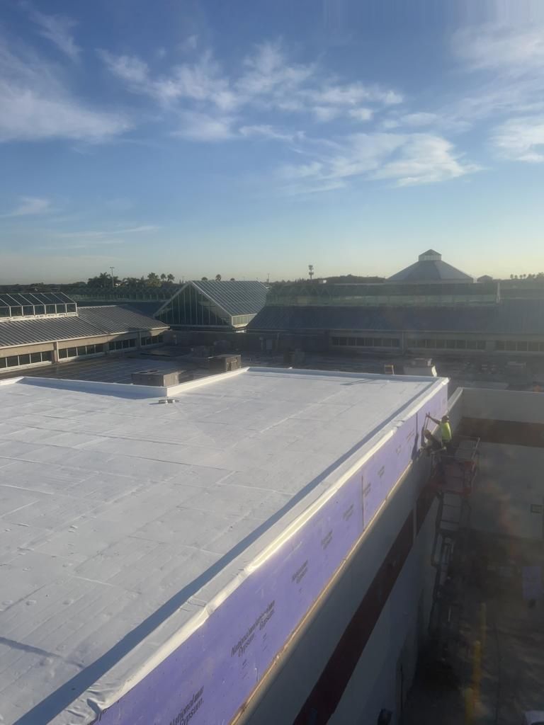 A large building with a white roof and a blue sky in the background